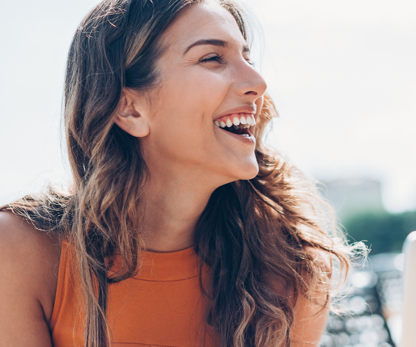 An yound woman laughs because she understands her thyroid disease and thyroid medication.