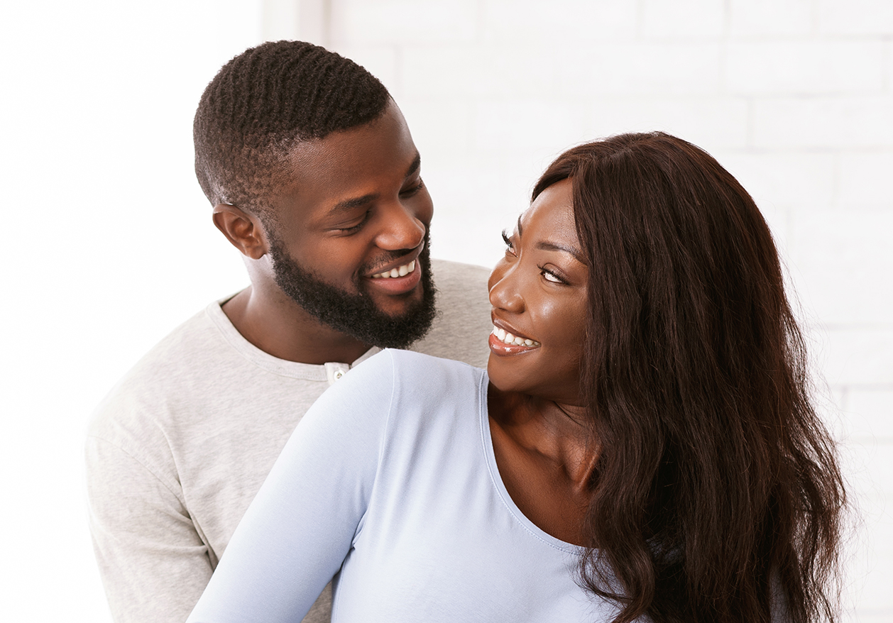 A black couple embraces while smiling because they successfully treated erectile dysfunction (ED).