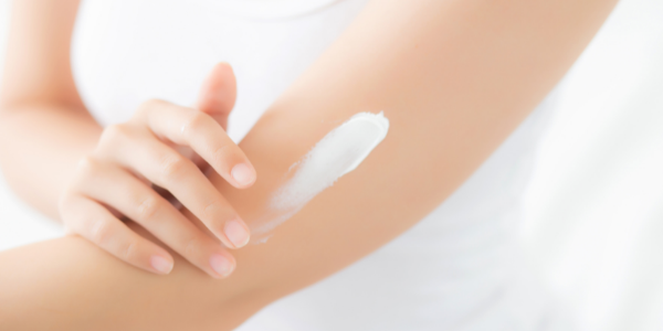 A close-up of a woman's upper arm as she applies progesterone cream.