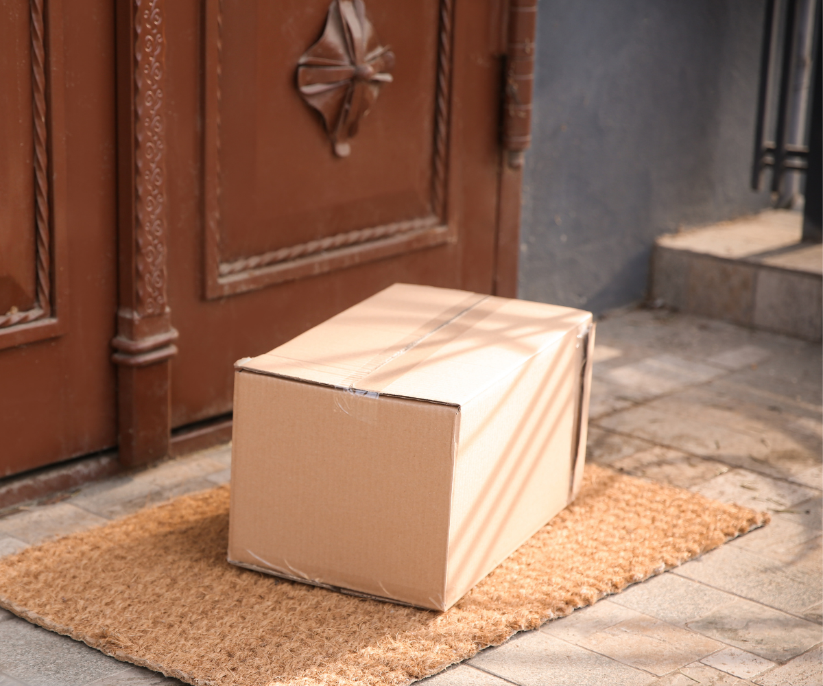 A brown package sitting outside of a wooden door.