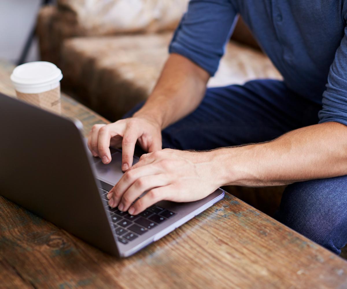 A man's hand and arm as he types on his laptop, searching for details about erectile dysfunction.