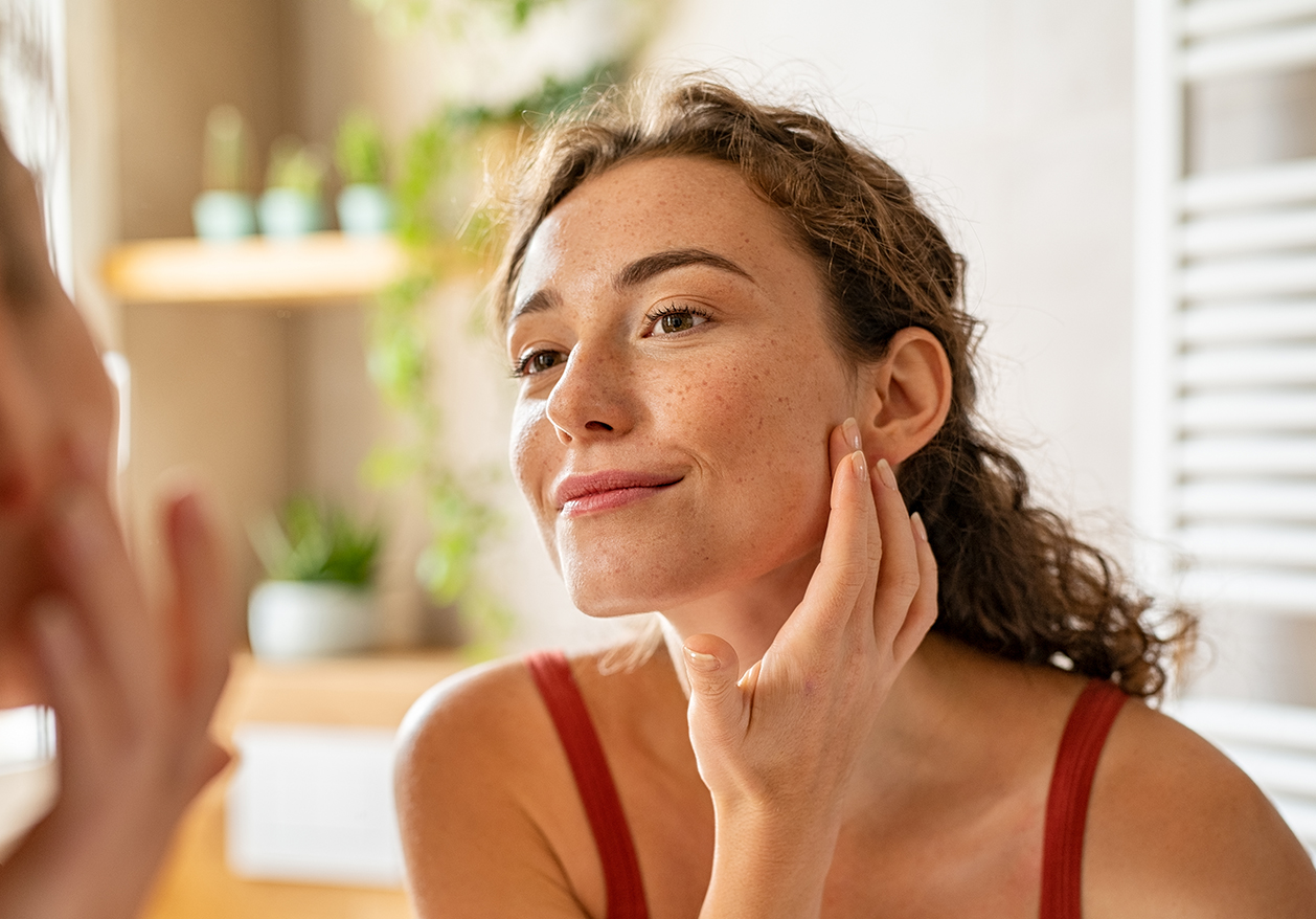 A woman admires her cosmetic injections in the mirror.