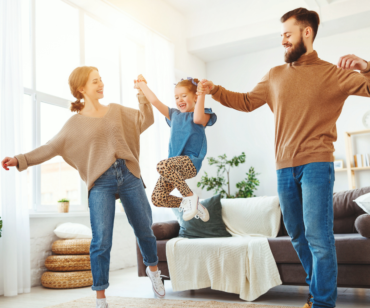 A mother and father lift their child while they all smile.