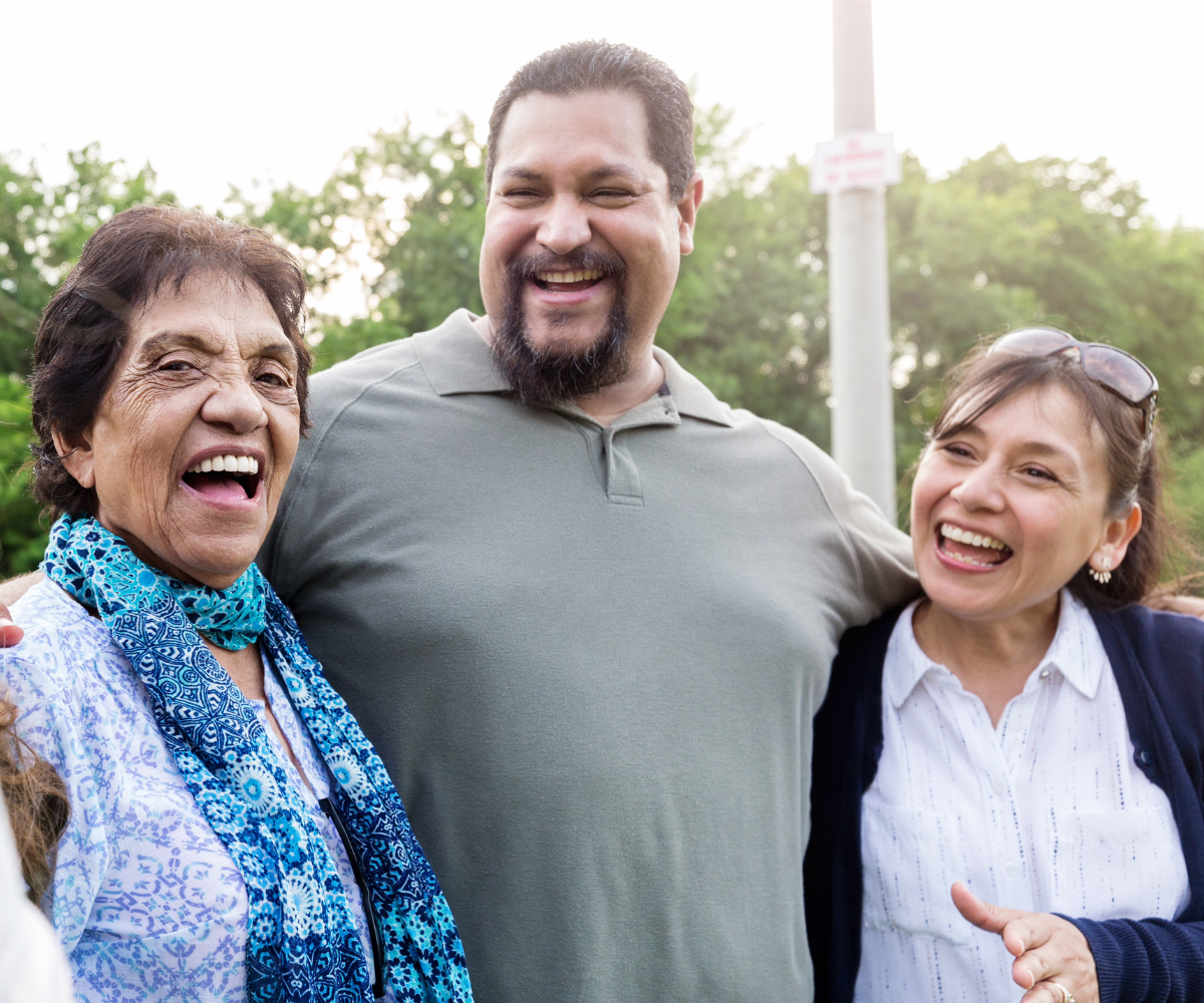 A plus-sized men laughs and smiles with his wife and mother.