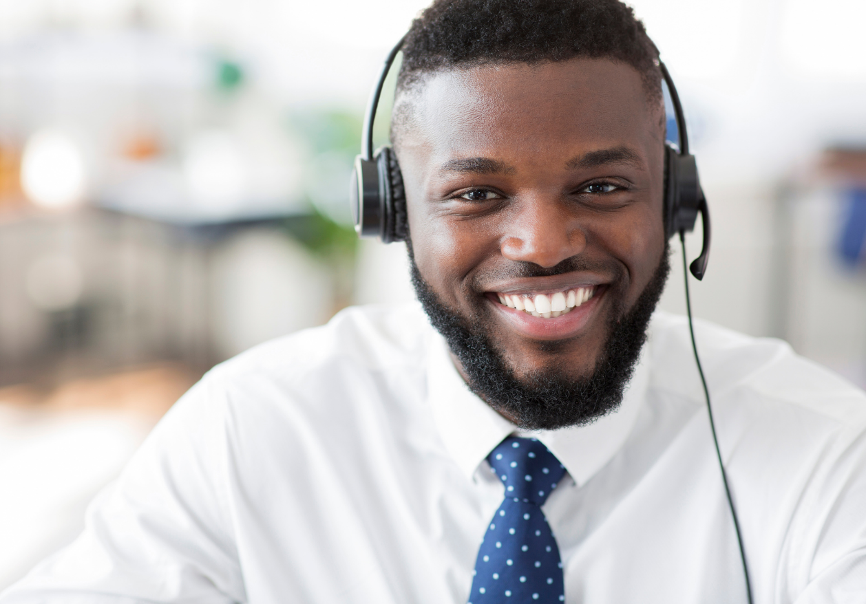 A male customer service representative smiles at the camera while wearing a headset.