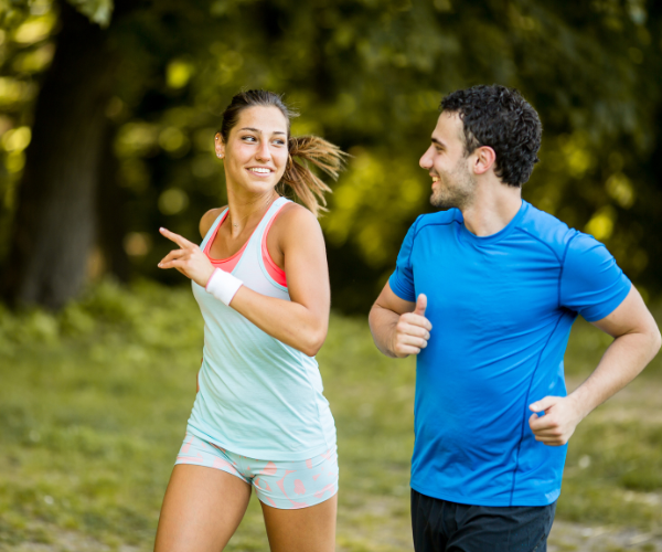 Man and woman running together and smiling at one another