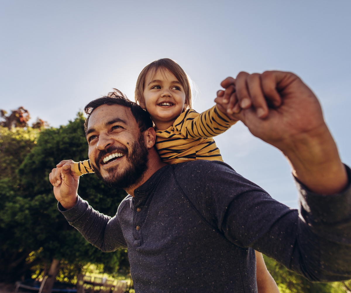 Man smiles with his daughter on his back because TRT has improved his mood.