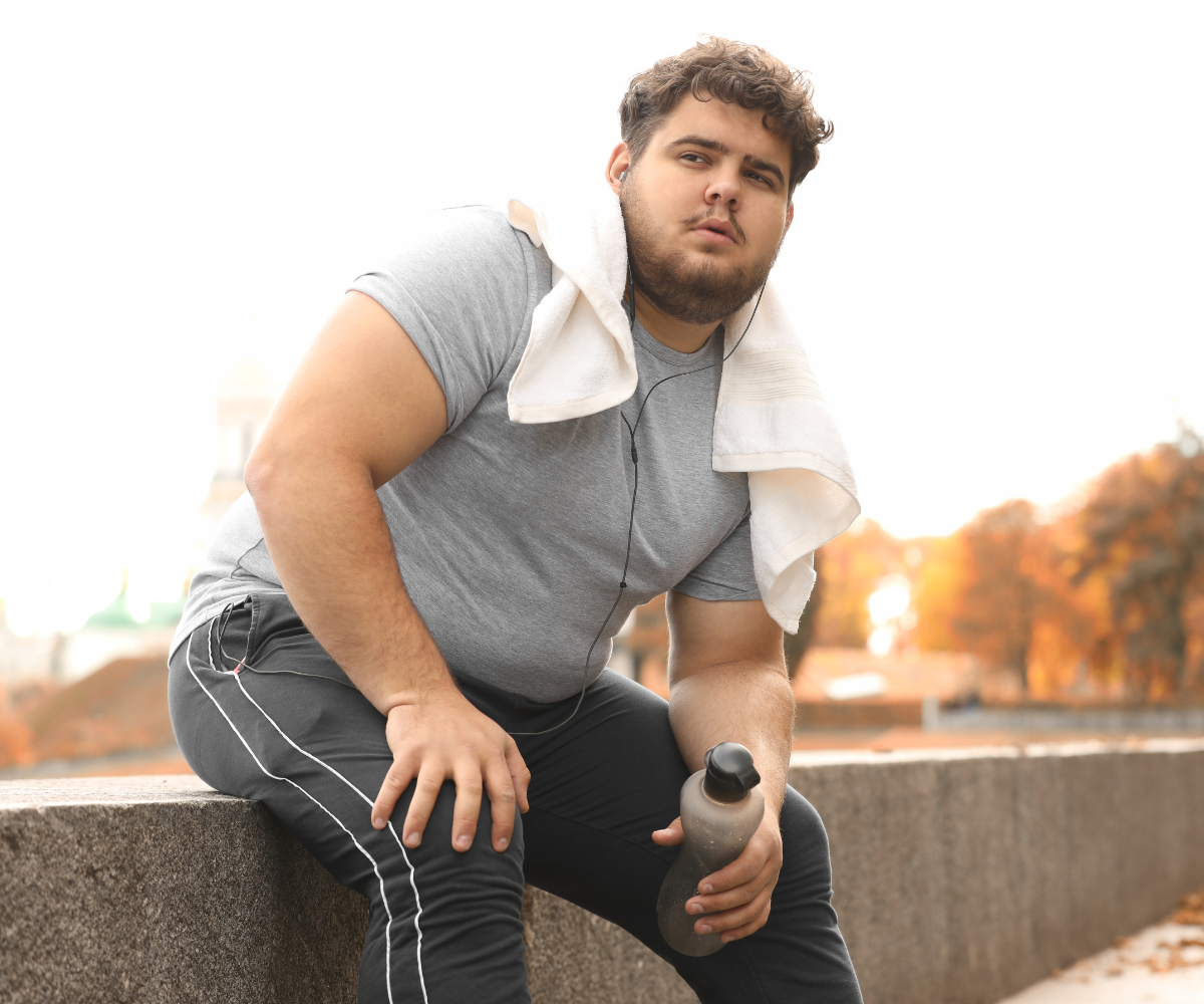 A plus-sized man takes a break from exercising outdoors