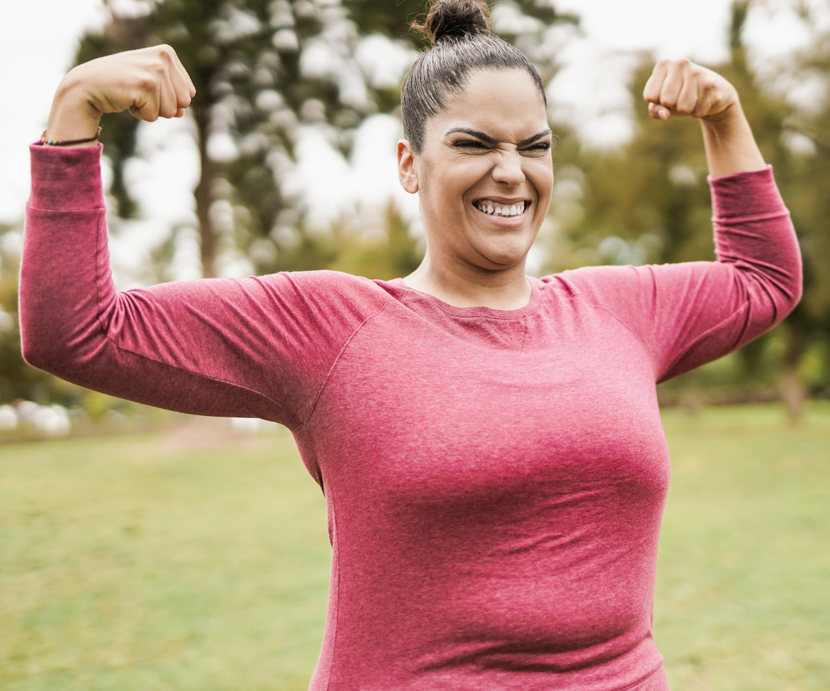 A woman smiles as she shows off her weight loss progress.