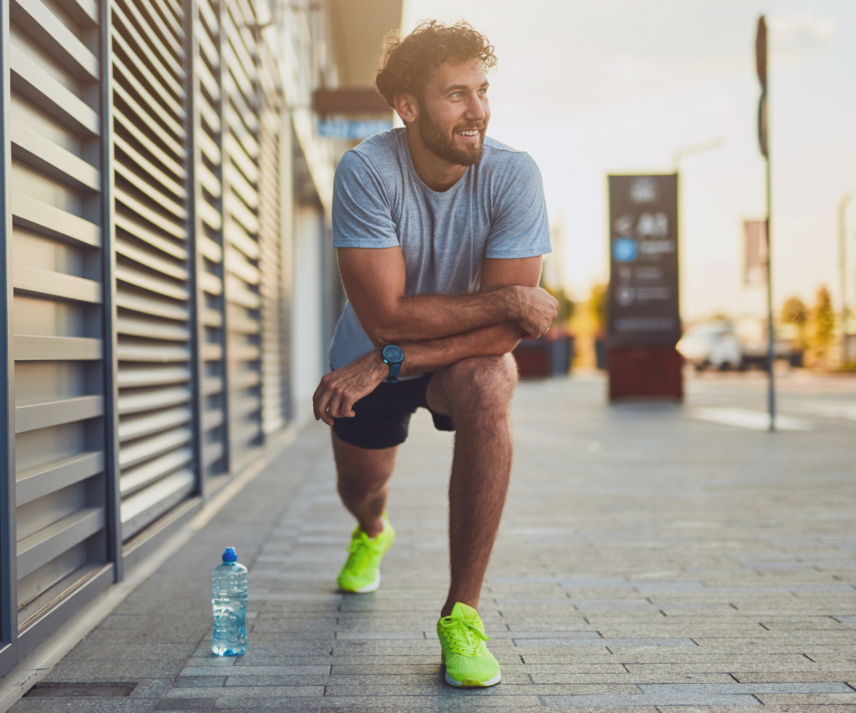 A man stretches as he exercising, smiling because his workout routine goes better after increasing his Testosterone.