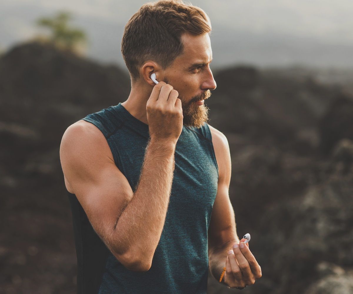 A man puts his earbud in his ear as he goes for a run.